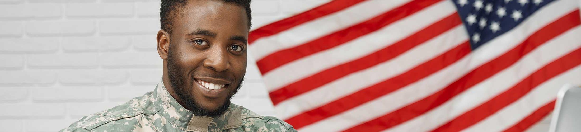 Veteran male standing next to American flag.